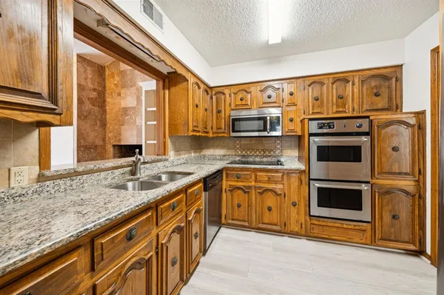 a kitchen with stainless steel appliances granite countertop a stove a sink and a microwave