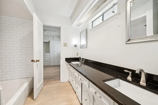 a spacious bathroom with a granite countertop sink and a bathtub