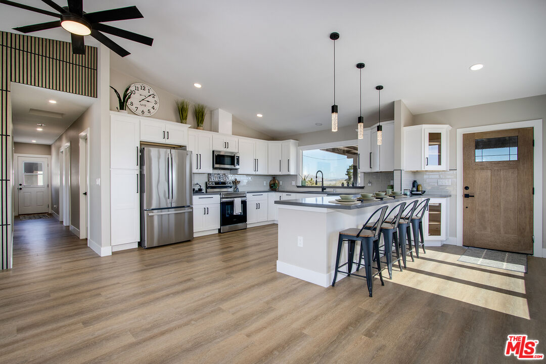 a kitchen with stainless steel appliances granite countertop a refrigerator a stove top oven a sink dishwasher and a dining table with wooden floor