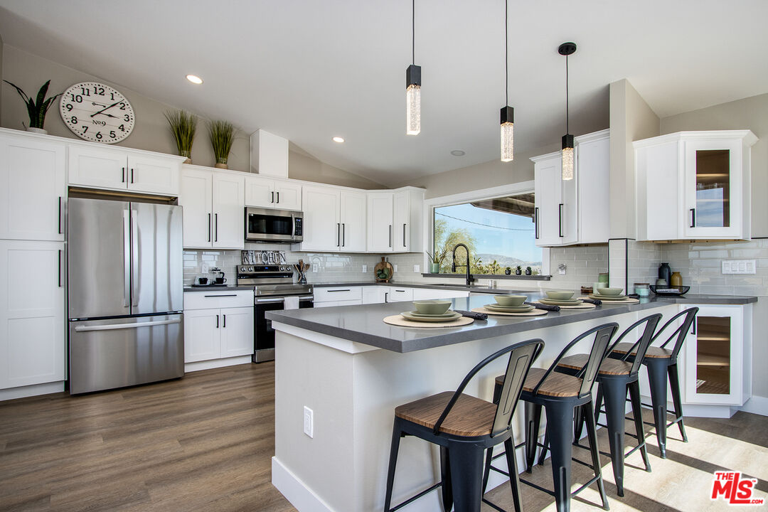 60777 Adele Road Landers, CA 92285 - Photo 11 of 43 a kitchen with stainless steel appliances granite countertop a sink a stove a refrigerator and a dining table with wooden floor
