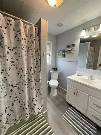 a kitchen with stainless steel appliances a stove a sink dishwasher a refrigerator white cabinets and wooden floor