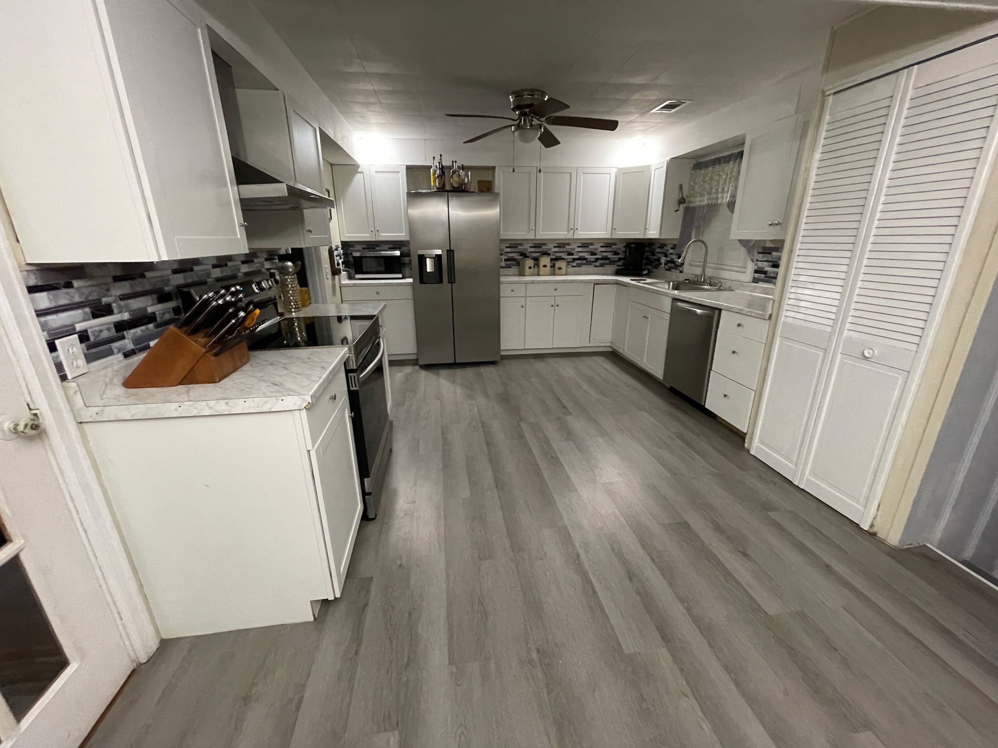 4426 Glasgow Road Burkesville, KY 42717 - Photo 20 of 24 a kitchen with stainless steel appliances a stove a sink dishwasher a refrigerator white cabinets and wooden floor