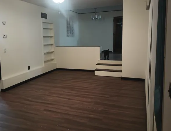 a view of an empty room with wooden floor and closet