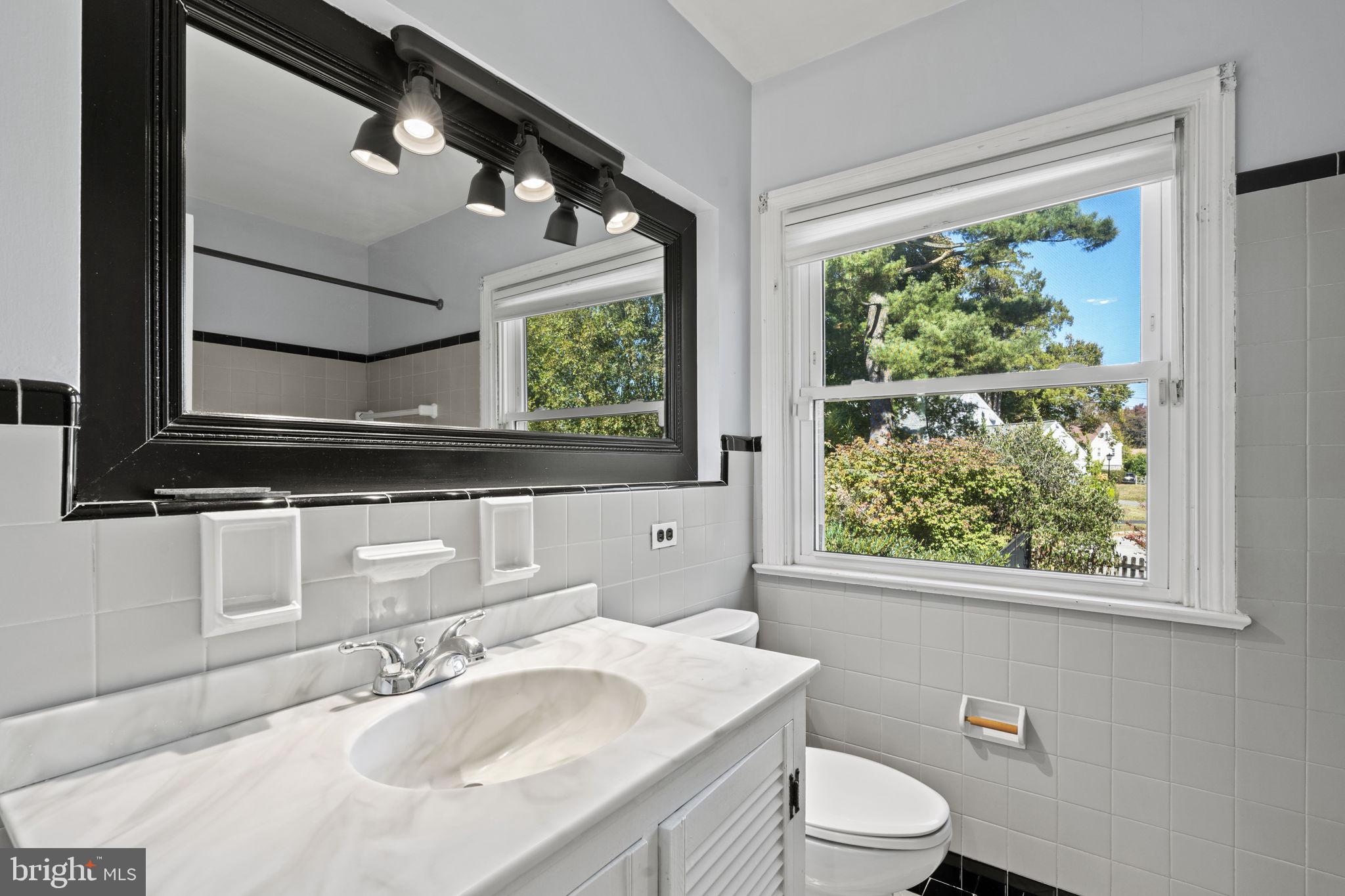 1007 Nicholson Road Wynnewood, PA 19096 - Photo 18 of 29 a bathroom with a toilet a sink a mirror and a window