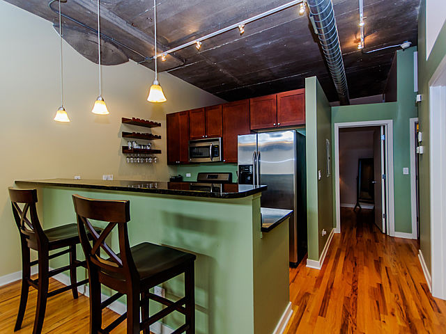 1111 West 15th Street, Unit 111 Chicago, IL 60608 - Photo 2 of 17 a kitchen with stainless steel appliances granite countertop a table chairs and a refrigerator