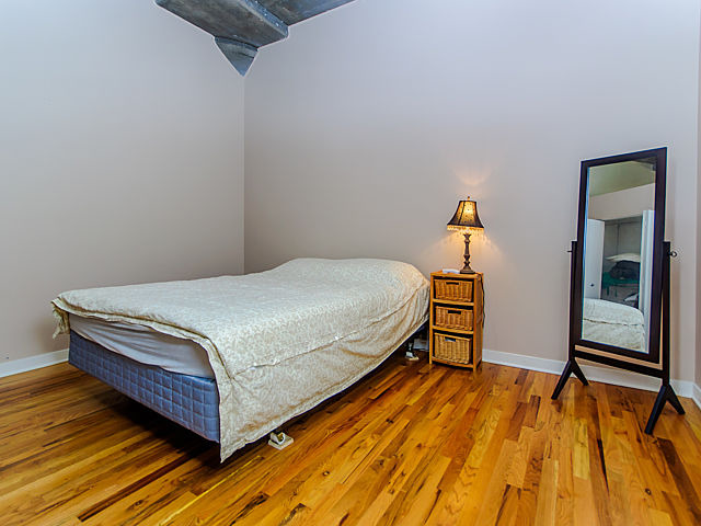 1111 West 15th Street, Unit 111 Chicago, IL 60608 - Photo 12 of 17 a bedroom with a bed and wooden floor