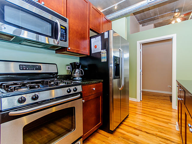 1111 West 15th Street, Unit 111 Chicago, IL 60608 - Photo 4 of 17 a kitchen with stainless steel appliances granite countertop a stove and a refrigerator