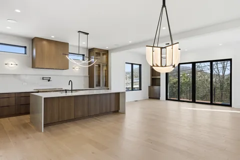 a view of a kitchen with stainless steel appliances granite countertop a stove top oven a sink with wooden floor