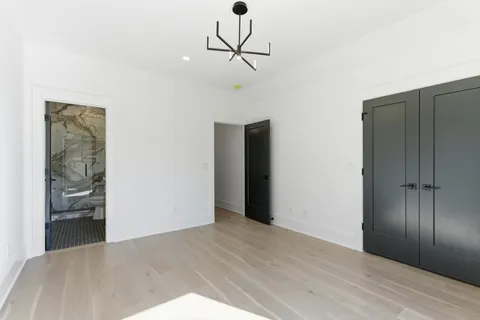 an empty room with wooden floor chandelier and windows