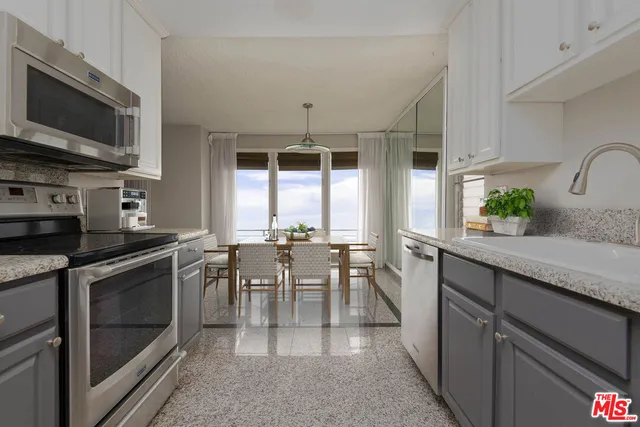 a kitchen with stainless steel appliances granite countertop a stove top oven a sink a dining table and chairs