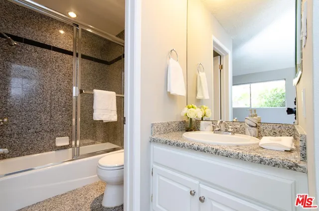 a bathroom with a granite countertop sink toilet and shower