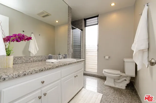 a bathroom with a granite countertop sink mirror and toilet