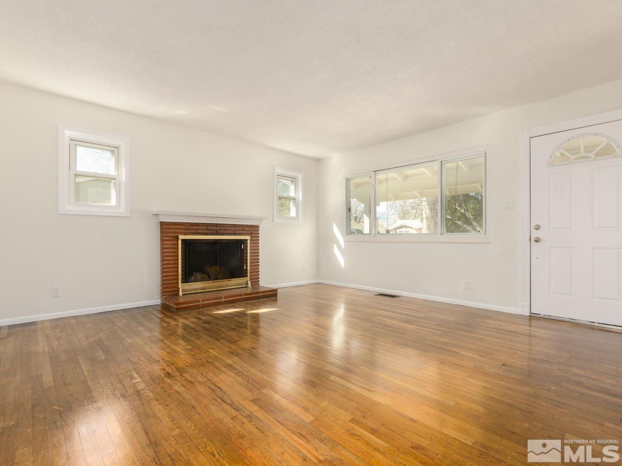 4620 Azalea Drive Reno, NV 89502 - Photo 2 of 19 an empty room with wooden floor fireplace and windows