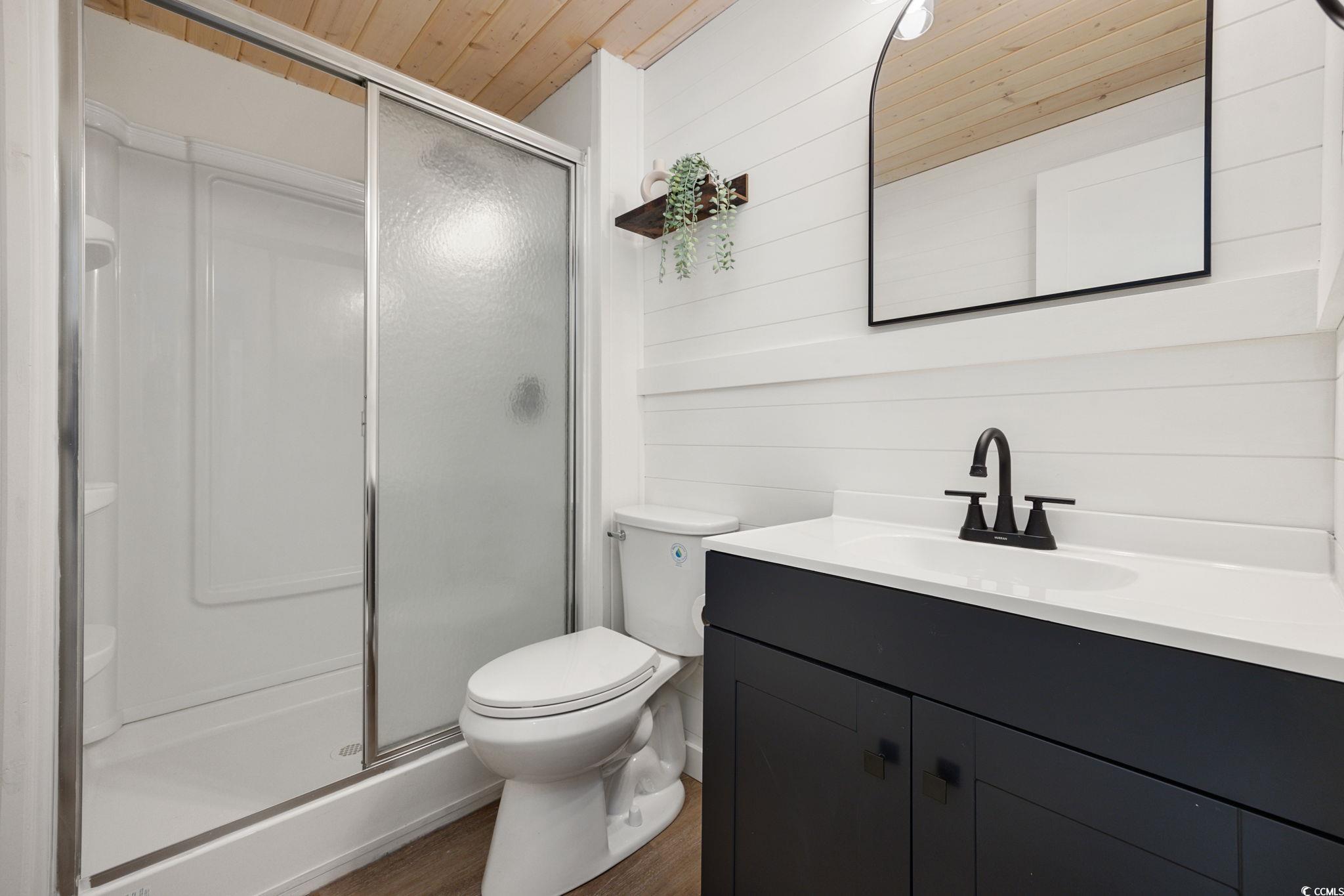 983 South Marlin Circle Murrells Inlet, SC 29576 - Photo 16 of 40 Bathroom with vanity, a stall shower, wood finished floors, wood ceiling, and wood walls