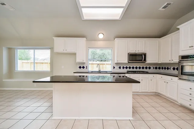 a kitchen with granite countertop white cabinets and white appliances