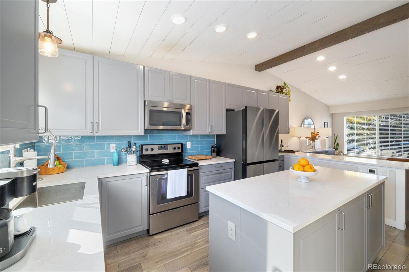 a kitchen with a refrigerator a stove a oven a sink dishwasher and a dining table with wooden floor