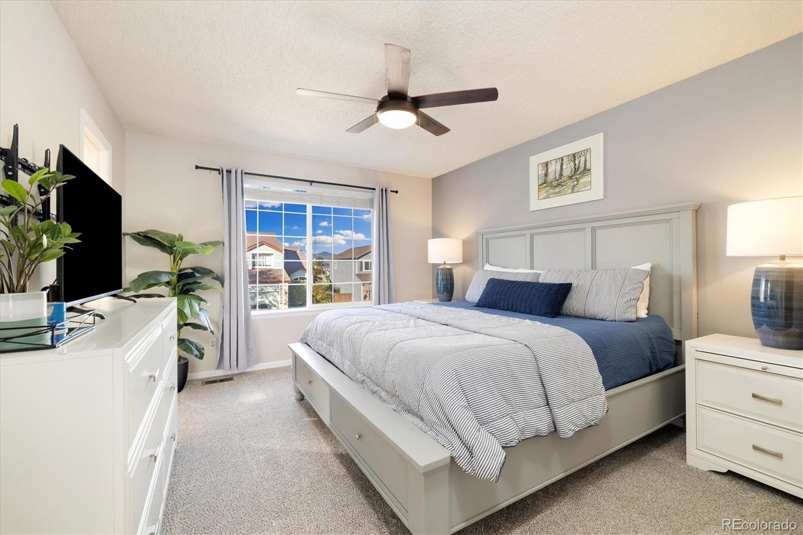 9823 South Castle Ridge Circle Highlands Ranch, CO 80129 - Photo 20 of 46 a spacious bedroom with a bed flat screen tv and a large window