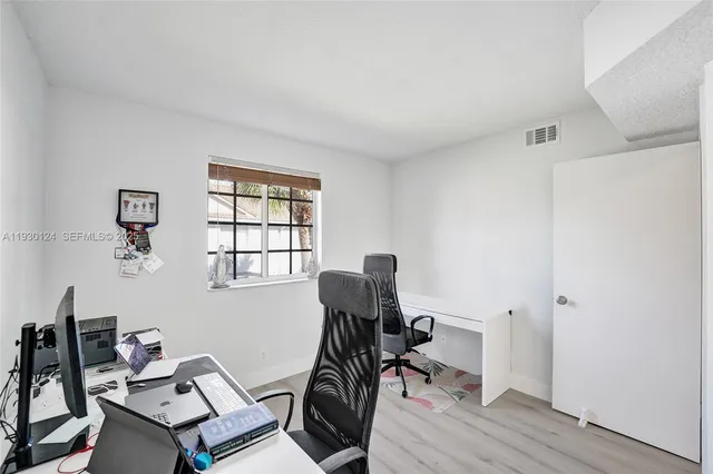 a hallway with white cabinets and wooden floor