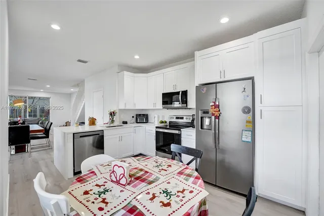 a kitchen that has a refrigerator a stove a sink a dining table and chairs