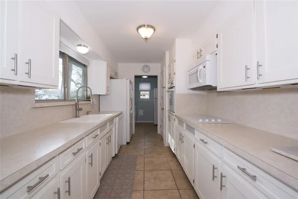a kitchen with granite countertop a sink and dishwasher a stove top oven with white cabinets