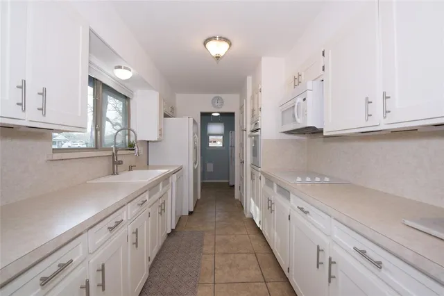 a kitchen with granite countertop a sink and dishwasher a stove top oven with white cabinets