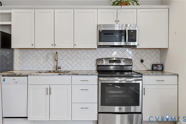a kitchen with granite countertop white cabinets and stainless steel appliances