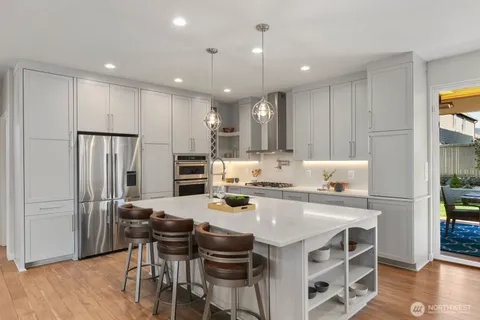 a kitchen with a stove a refrigerator and a dining table with wooden floor