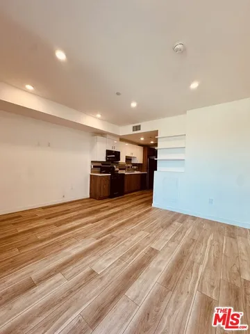 a view of kitchen and empty room with wooden floor