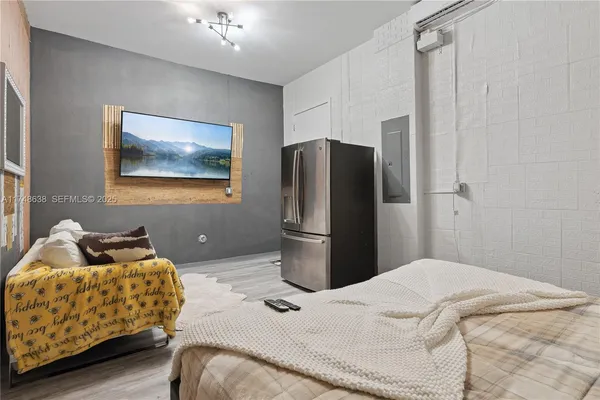 a bedroom with a bed and a refrigerator