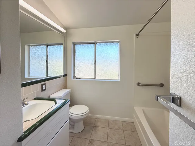 a bathroom with a granite countertop sink toilet and mirror