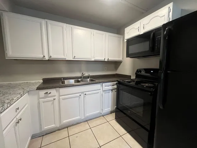 a kitchen with granite countertop white cabinets stainless steel appliances and sink