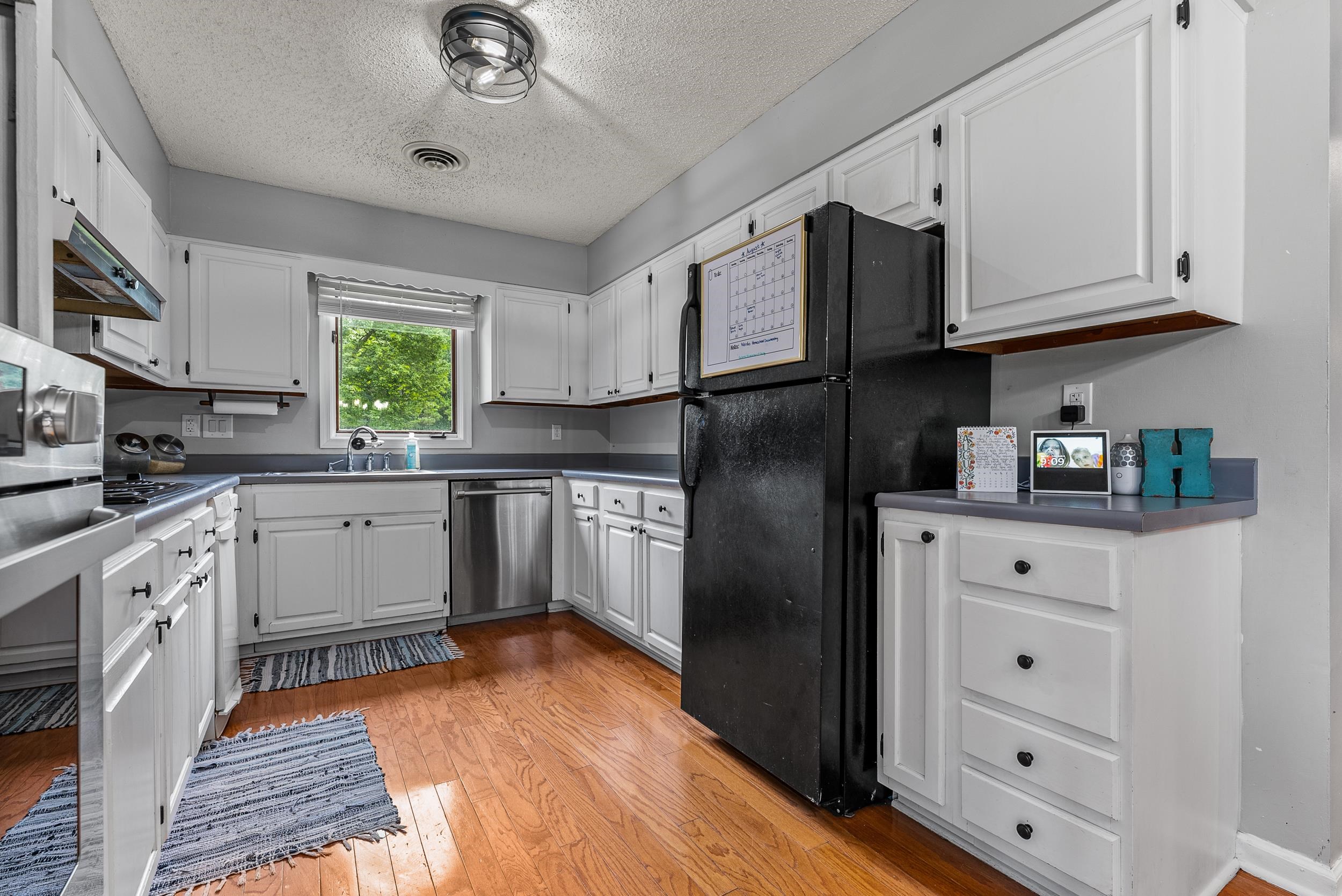 12389 Macon Road Collierville, TN 38017 - Photo 11 of 37 Kitchen with dishwasher, black refrigerator, white cabinetry, and light hardwood / wood-style floors