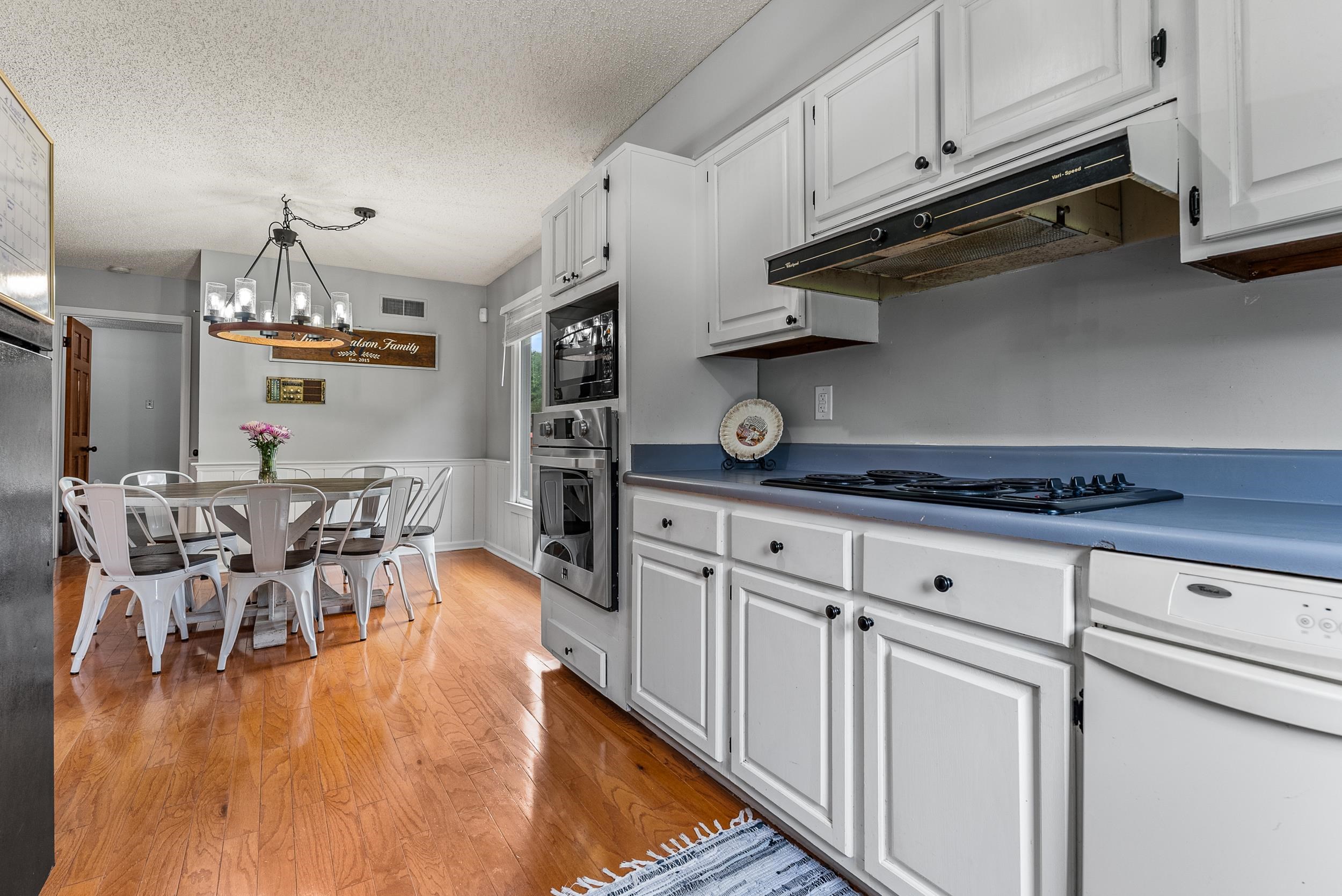 12389 Macon Road Collierville, TN 38017 - Photo 12 of 37 Kitchen featuring light hardwood / wood-style flooring, white cabinets, hanging light fixtures, black appliances, and a notable chandelier