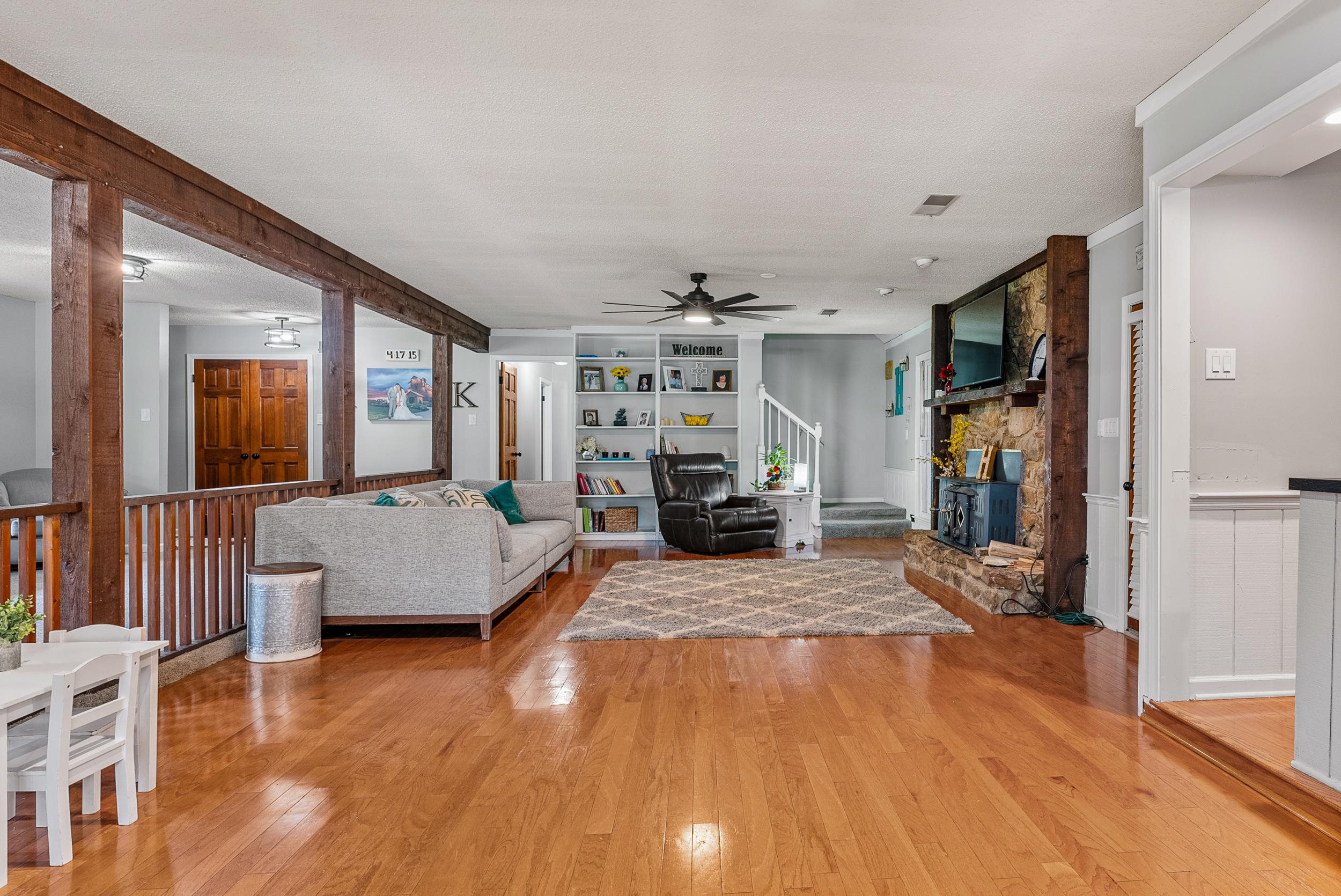 12389 Macon Road Collierville, TN 38017 - Photo 13 of 37 Unfurnished living room featuring ceiling fan, a stone fireplace, and light hardwood / wood-style floors