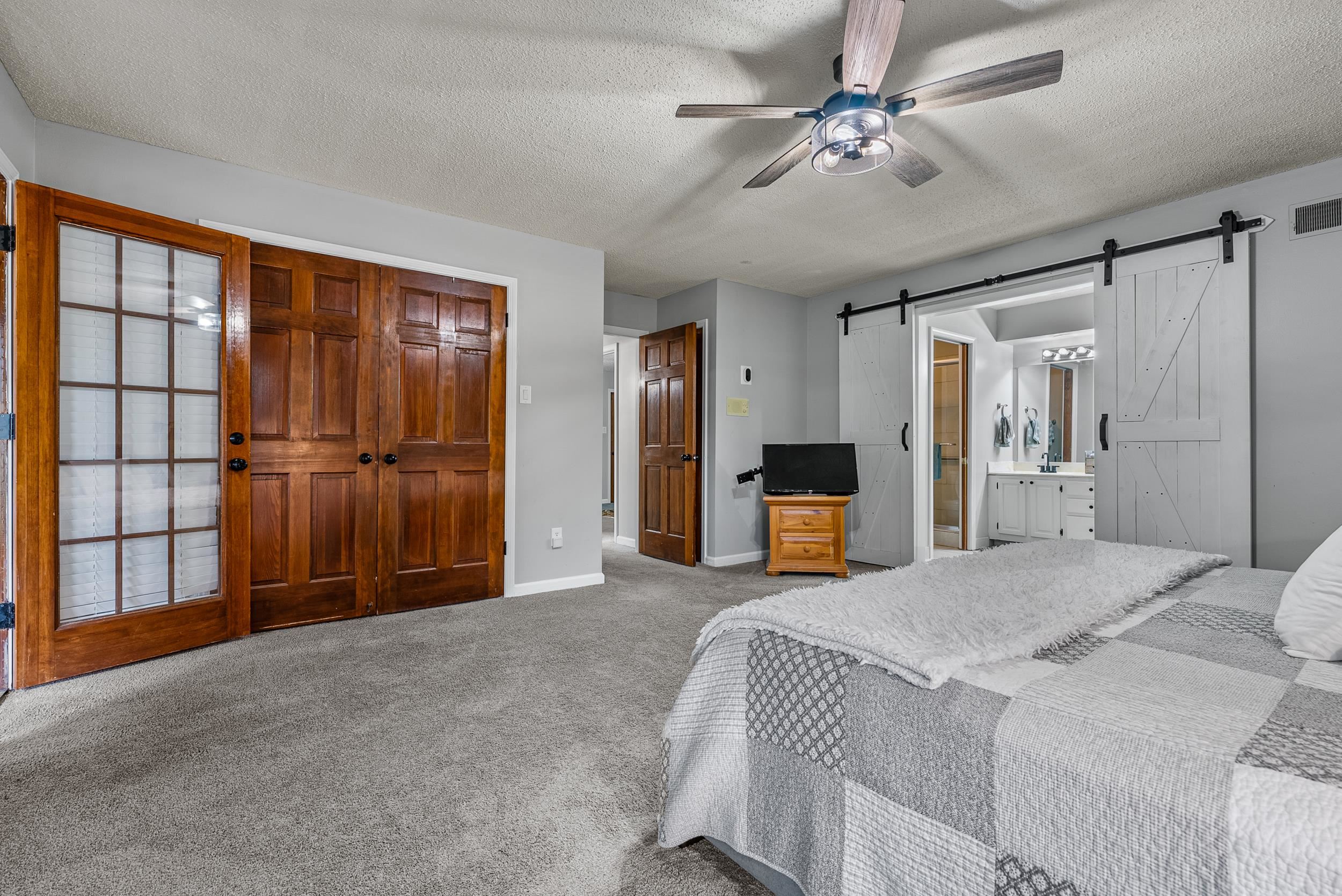 12389 Macon Road Collierville, TN 38017 - Photo 24 of 37 Bedroom featuring a barn door, a textured ceiling, ceiling fan, carpet floors, and ensuite bathroom