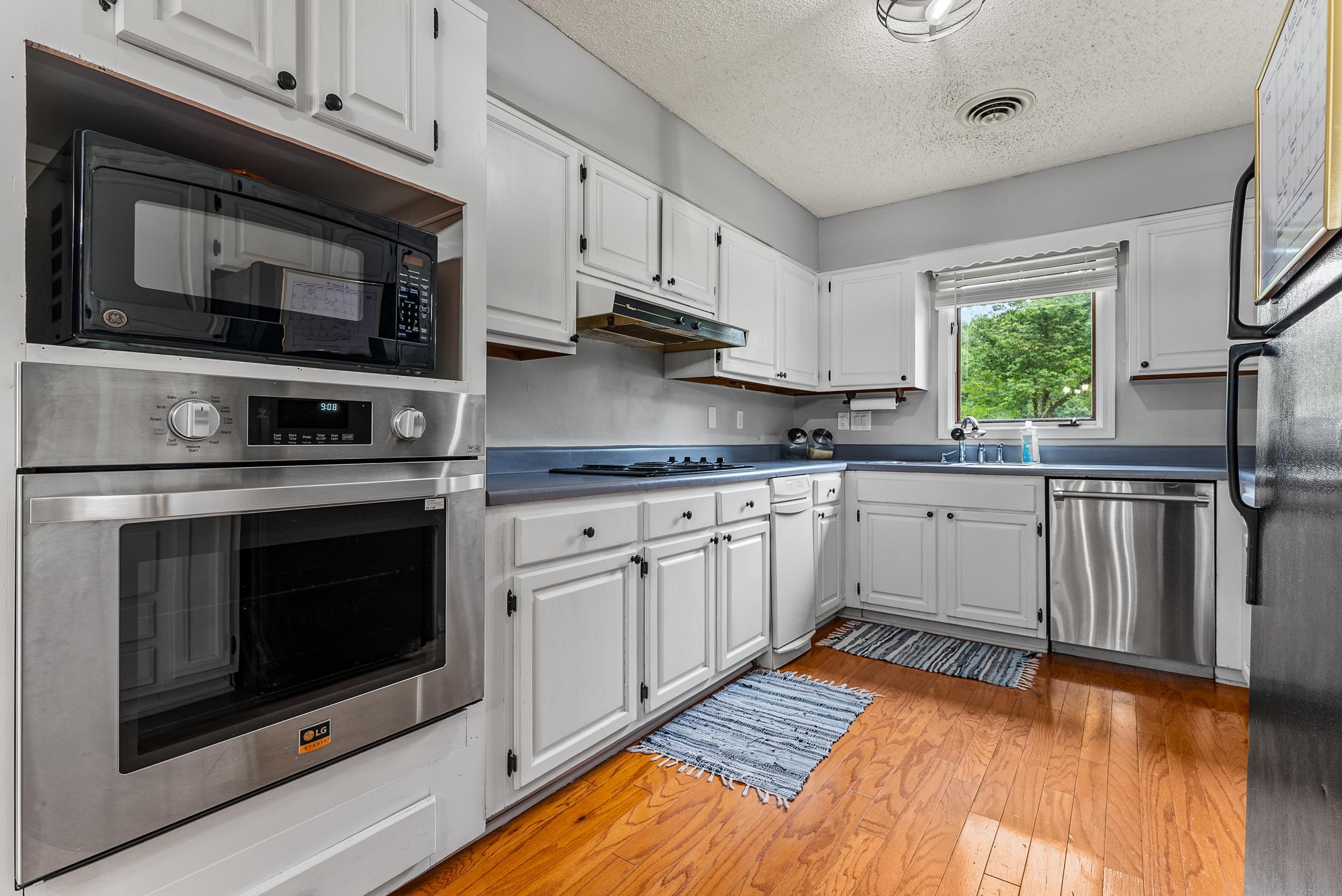 12389 Macon Road Collierville, TN 38017 - Photo 10 of 37 Kitchen with light hardwood / wood-style flooring, a textured ceiling, white cabinetry, black appliances, and sink