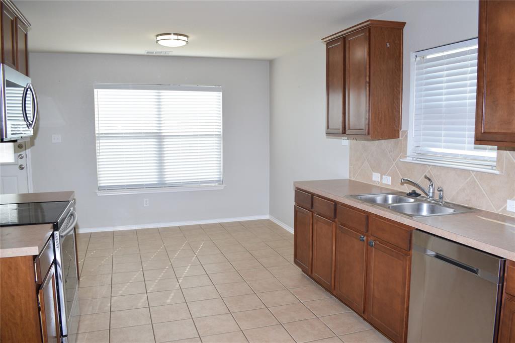 375 Housefinch Loop Leander, TX 78641 - Photo 8 of 28 Tiled flooring and warm wood cabinetry define this functional kitchen and adjacent dining area.