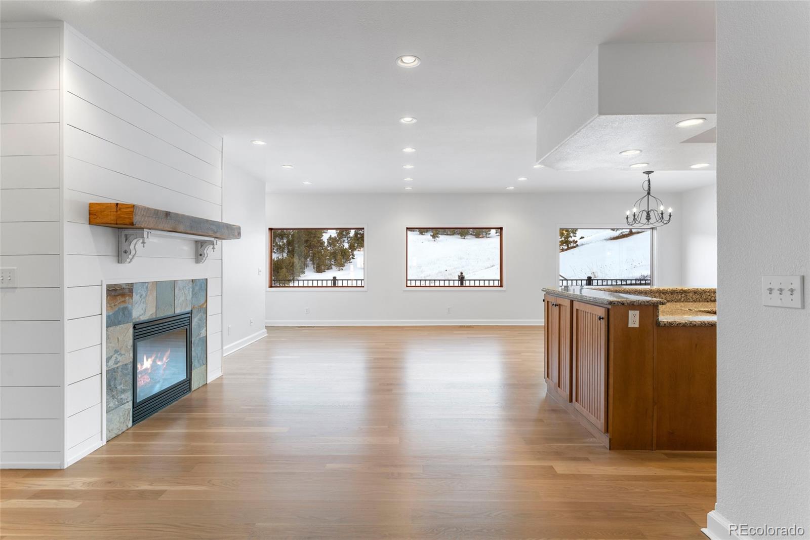 1305 South Grapevine Road Golden, CO 80401 - Photo 14 of 39 a view of a kitchen and an empty room with wooden floor and a fireplace