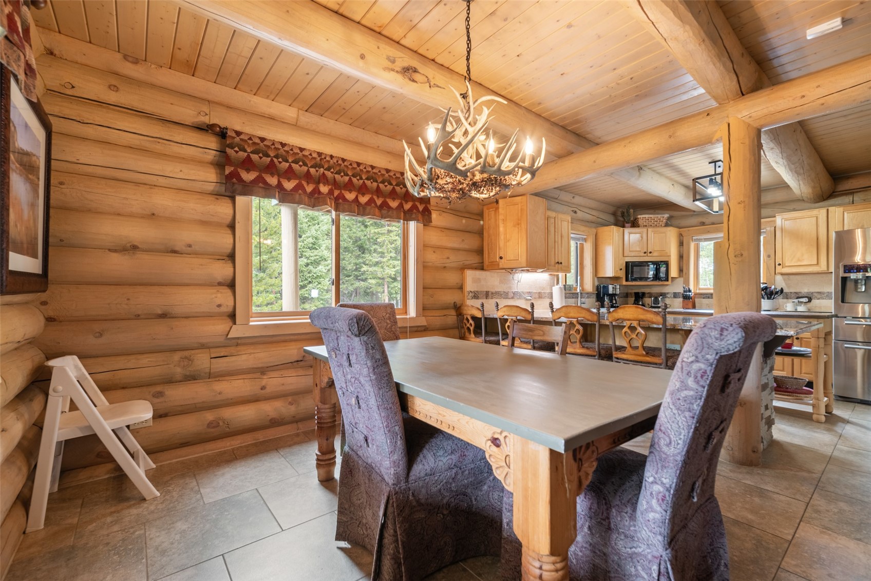 243 Rena Road Breckenridge, CO 80424 - Photo 22 of 50 Dining area featuring beamed ceiling, wood ceiling, light tile floors, log walls, and a chandelier