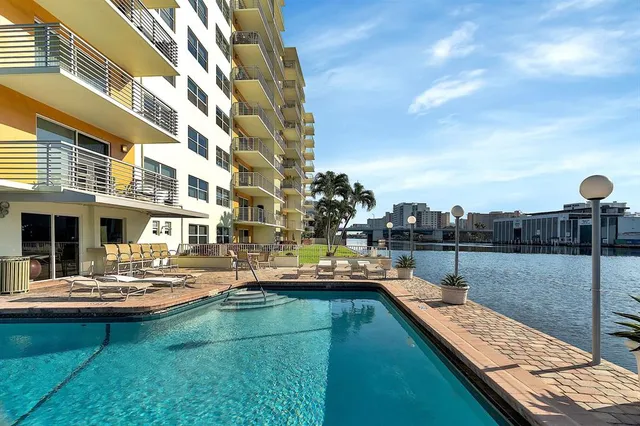 a view of swimming pool and lounge chairs in back yard of the house