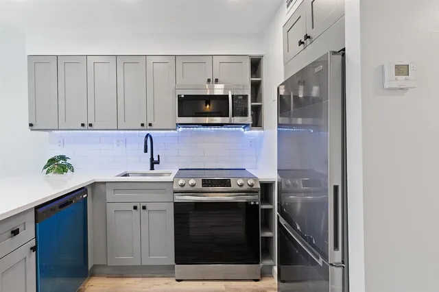 a kitchen with stainless steel appliances a stove a sink and a microwave