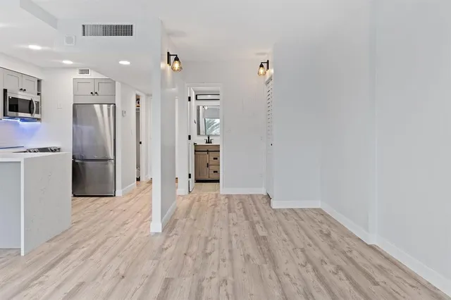 a view of a kitchen with wooden floor and a refrigerator