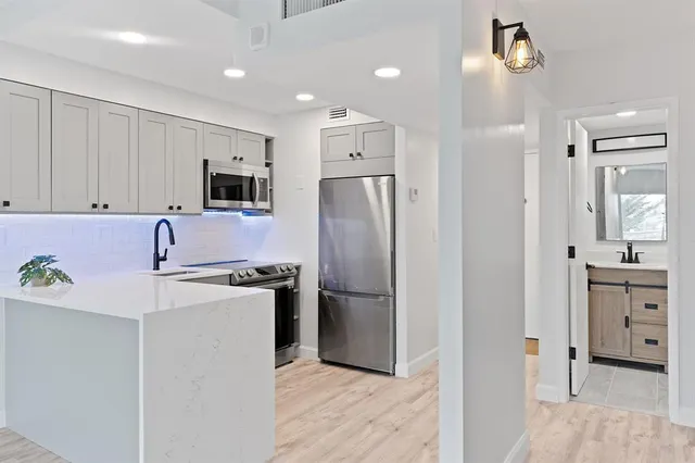 a kitchen with stainless steel appliances a refrigerator sink and white cabinets