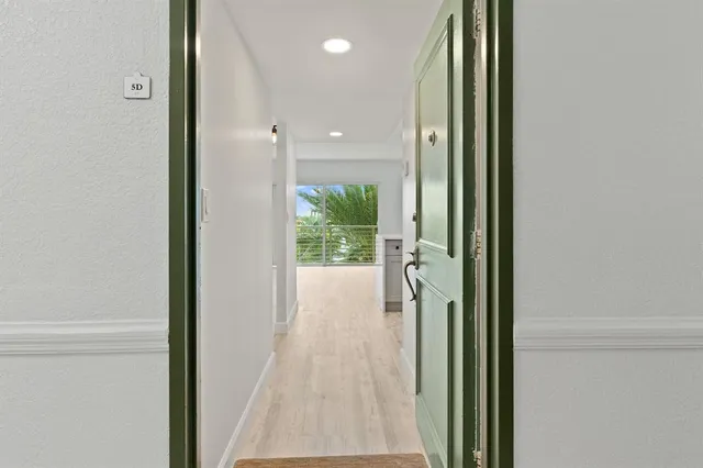a view of a hallway with wooden floor and a bathroom