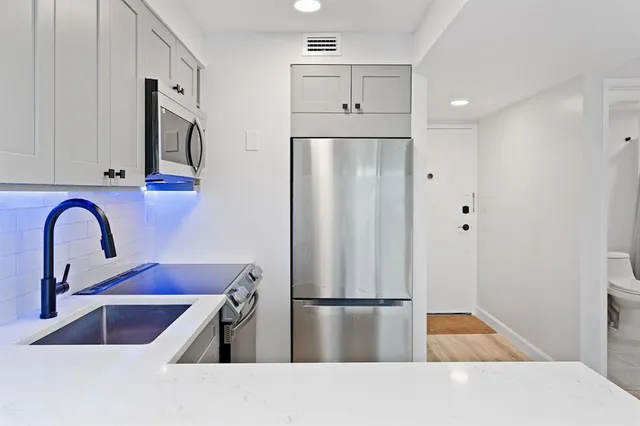 a kitchen with stainless steel appliances granite countertop a refrigerator and a sink