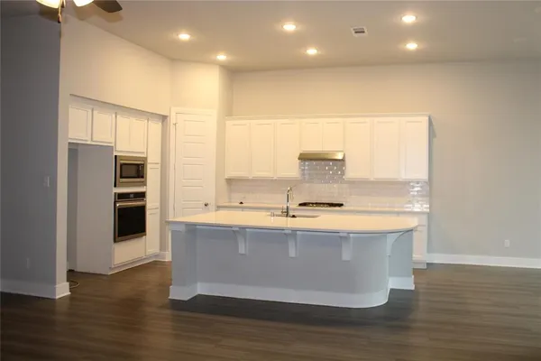 a view with kitchen island a sink a counter top space and stainless steel appliances