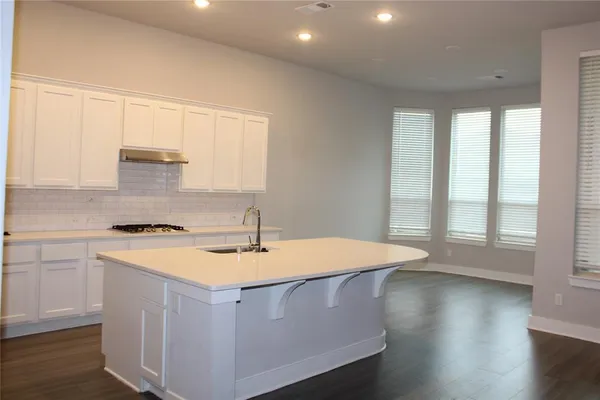 a kitchen that has a sink a stove and wooden floor