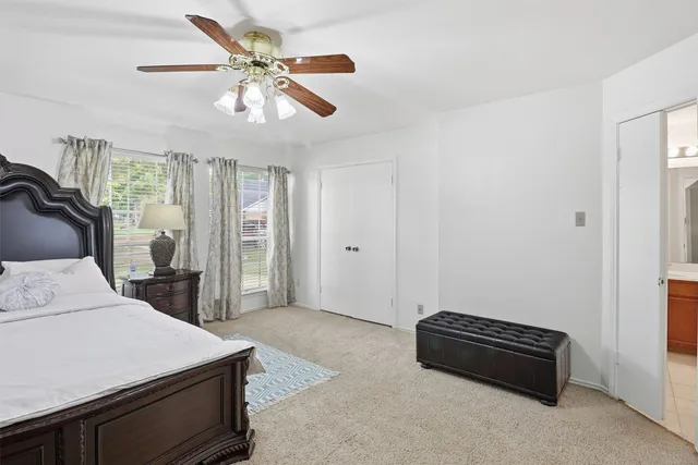 a spacious bedroom with a large bed and a chandelier fan