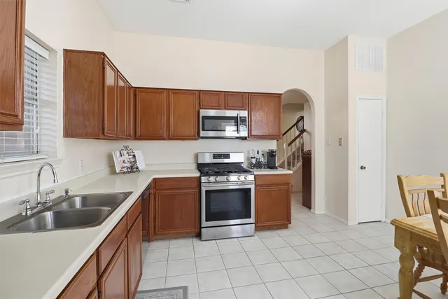 a kitchen with stainless steel appliances granite countertop a refrigerator a stove a sink dishwasher a dining table and chairs with wooden floor