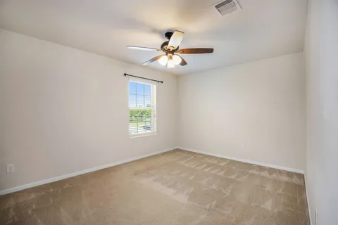 an empty room with a window and a fan